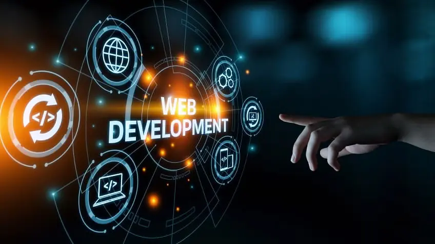 Developer collaborating on code shown on dual monitors, displaying a responsive website design and a native mobile app interface simultaneously.